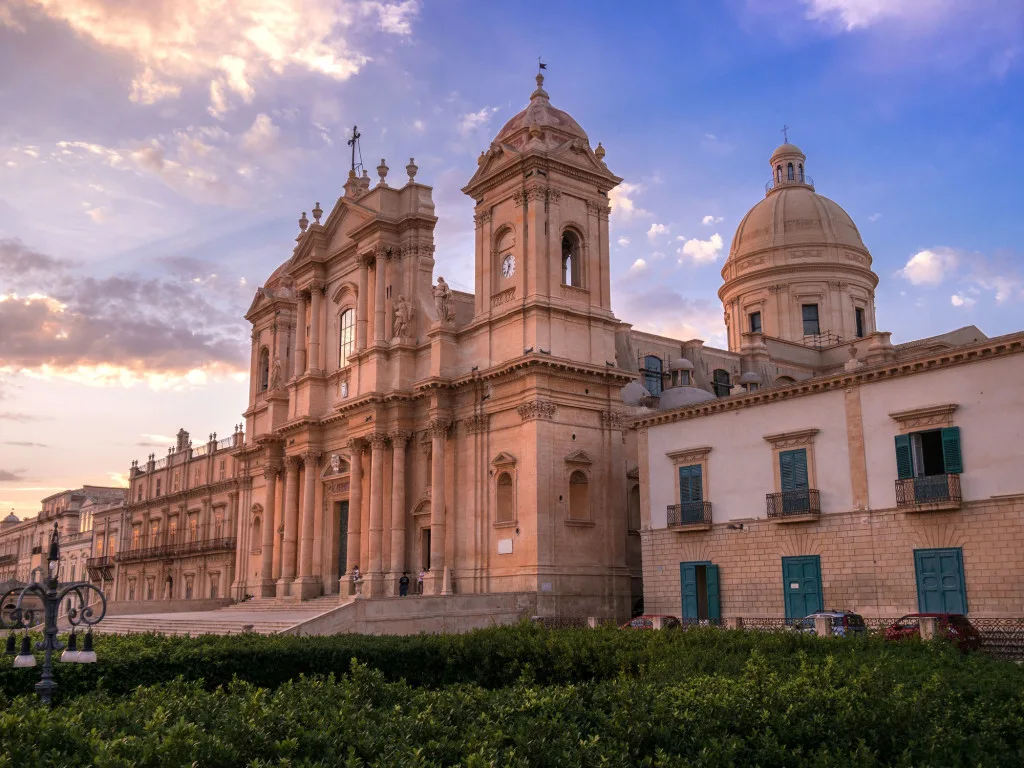 Elegant destination wedding couple portrait in front of the historic Palazzo Nicolaci in Noto.