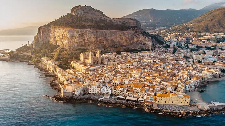 Panoramic view of the charming coastal town of Cefalù meeting the clear Mediterranean Sea in Sicily.