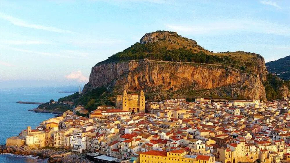 Scenic view of the historic waterfront buildings and tranquil blue sea in Cefalù.
