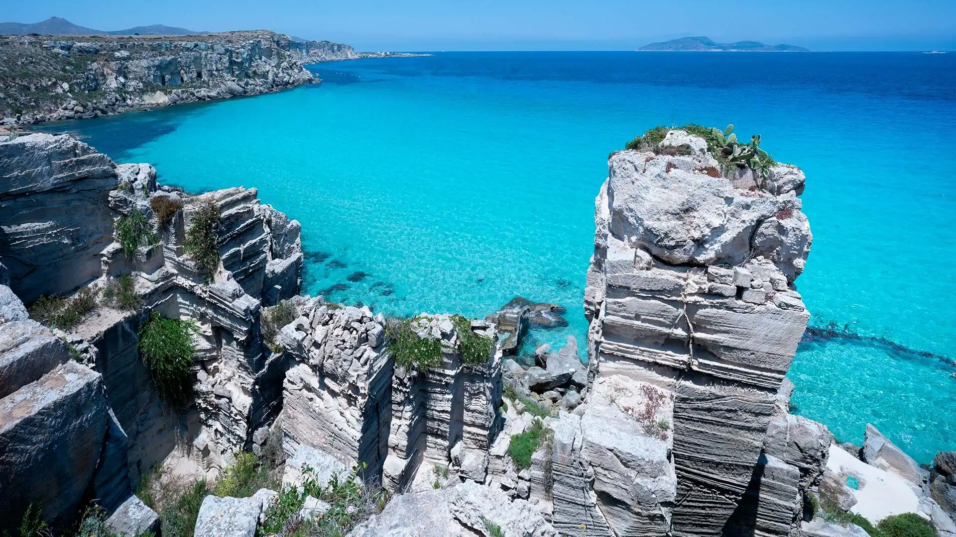 Crystal-clear turquoise waters and dramatic coastal rock formations on the island of Favignana, Sicily.