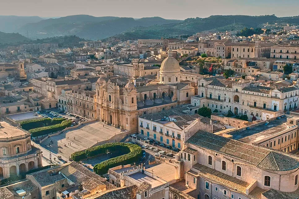 Bride and groom holding hands on the grand staircase of Noto Cathedral in Sicily.