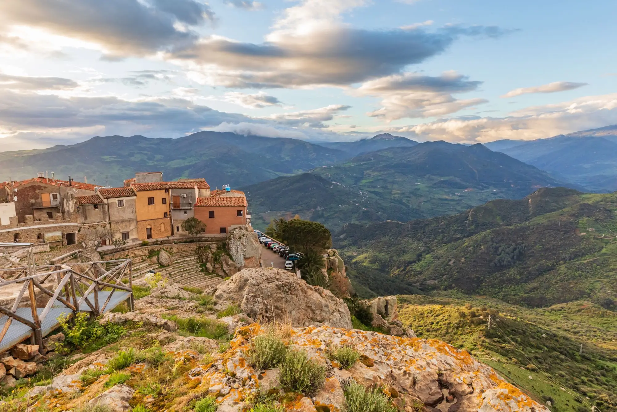 Warm golden hour sunlight illuminating the lush mountainous landscape and historic townscape of Castelbuono.
