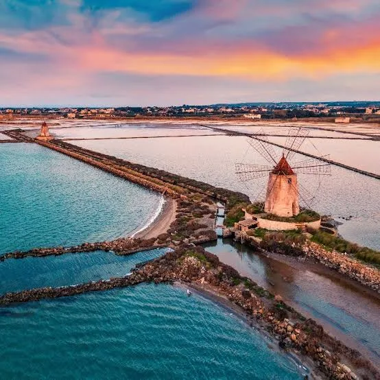 Breathtaking golden hour sunset reflecting over the tranquil coastal waters of Marsala, Sicily.