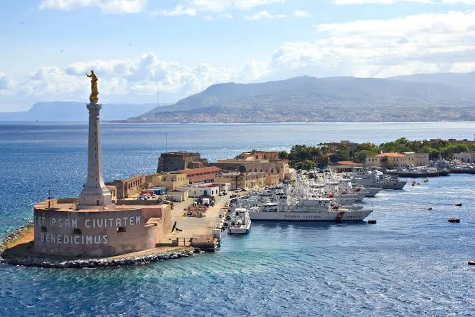 olden hour sunset casting warm light over the waterfront and picturesque coastline of Messina, Sicily.
