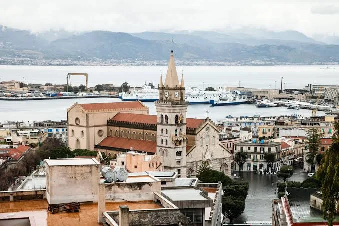 olden hour sunset casting warm light over the waterfront and picturesque coastline of Messina, Sicily.