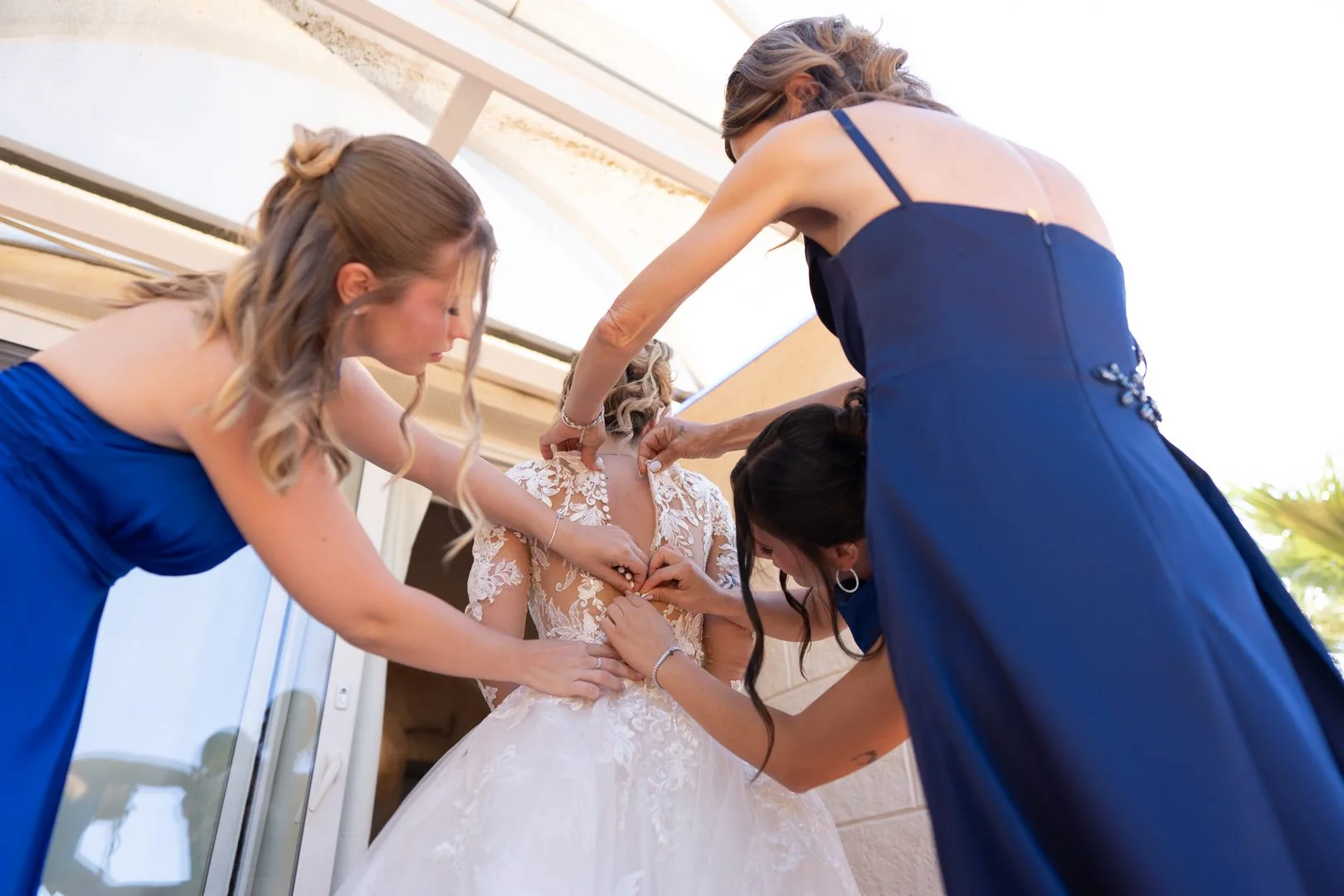 Bridesmaids fastening the back of the bride's wedding dress