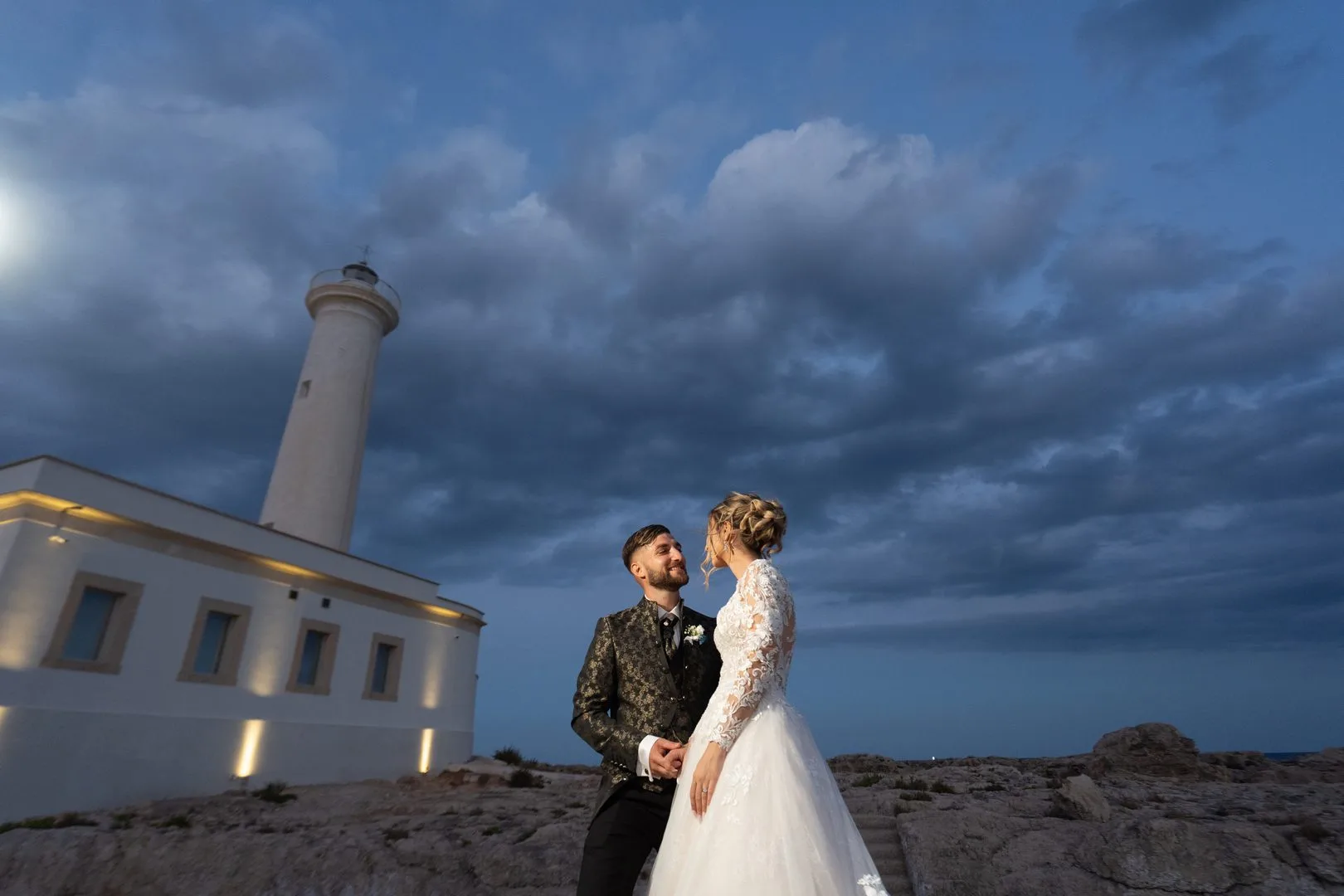 Bride and groom embracing at the Capo Santa Croce lighthouse in Augusta, Sicily.
