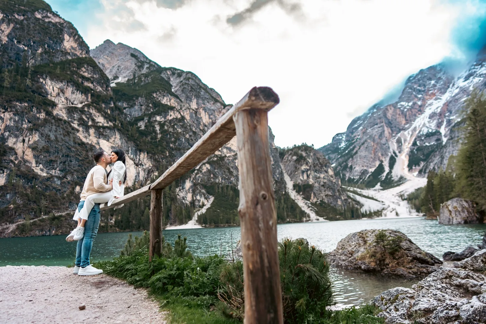 bride and groom sitting on a wooden fence overlooking a picturesque lake in Sicily